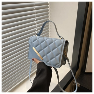 Détail du sac à main matelassé bleu clair avec barre métallique dorée et anse