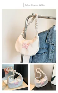 Detail of white half-moon bag featuring pink butterfly embroidery and ruffled strap