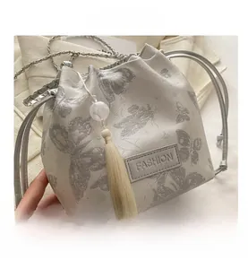 Detail der Canvas-Beuteltasche mit Schmetterlingsprint, Quastenanhänger und Kette