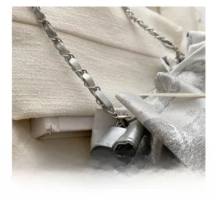 Makroaufnahme von silbernem Jacquard-Stoff und geflochtener Metallkette am Taschengurt