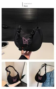 Detail of black crescent shoulder bag featuring pink butterfly embroidery and pleated handle