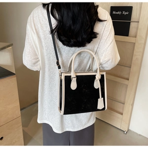 Elegante borsa tote a contrasto bianco e nero indossata a tracolla in un interno