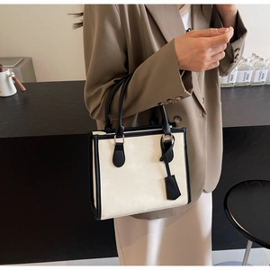 Dettaglio di una borsa tote crema chic con bordi neri a contrasto e manici eleganti