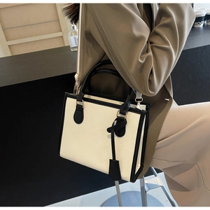 Dettaglio borsa tote bicolore alla moda indossata con abito formale per un look da ufficio