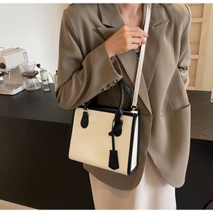 Elegante borsa tote beige con finiture nere in un caffè per uno stile urbano moderno