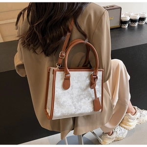 Borsa tote argento effetto marmo con finiture in pelle marrone indossata a spalla