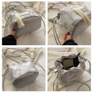 Detailsicht der silbergrauen Beuteltasche mit Schmetterlingsmuster und Quaste