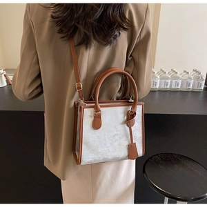 Borsa tote argento con finiture in pelle marrone indossata da una modella elegante