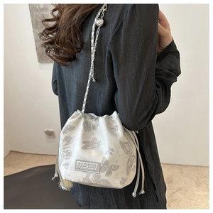 Detail der weißen Beuteltasche mit silbernen Schmetterlingsdrucken und Kettenriemen
