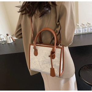 Dettaglio della borsa tote glitterata argento con manici in pelle marrone e tracolla
