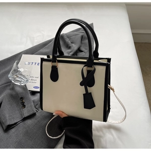 Borsa tote minimalista crema e nera esposta con accessori moda per uno stile professionale