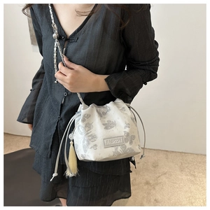 Detail der weißen Beuteltasche mit Schmetterlings-Jacquard und silberner Kette