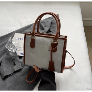 Dettaglio della borsa tote effetto marmo con manici in pelle marrone su sfondo neutro