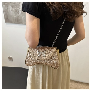 Detailed view of women's gold glitter chain bag with a stylish silver bow decoration