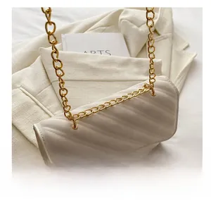 Close-up of golden chain strap and quilted leather texture on an off-white handbag