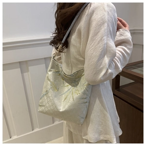 Detail of silk thread embroidery and bamboo leaf pattern on a light green shoulder bag