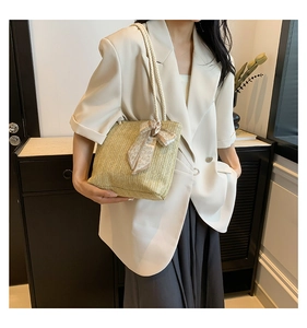 Détail du sac cabas en paille beige avec anses en corde blanche et nœud en soie à cœurs
