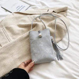 Dettaglio mini borsa grigia a tracolla con perla grande e nappa decorativa