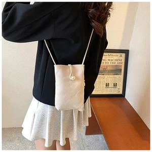 Crème mini crossbodytas met parelgesp en franjedetails gedragen door een model