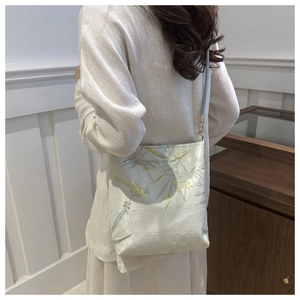 Detail of silk embroidery with bamboo and bird motifs on a white Chinese style shoulder bag