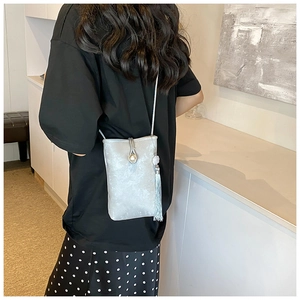 Detail van mini crossbodytas met parelsluiting en lange decoratieve kwastjes aan de zijkant