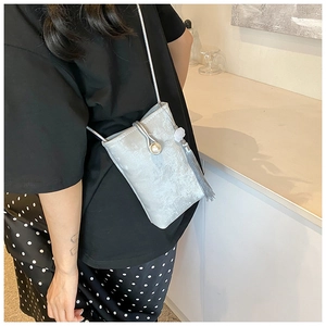 Detail van zilveren metallic crossbody tas met parelsluiting en grijze zijden kwastje