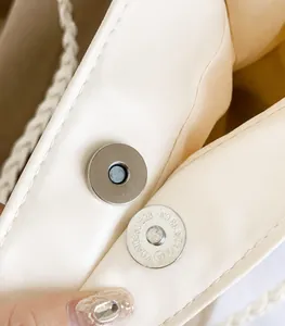 Detail of premium polished magnetic clasp and fine leather stitching on cream tote bag