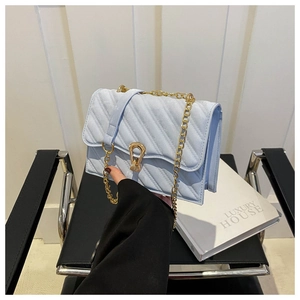 Detail of light blue quilted crossbody bag with gold chain strap and metal buckle