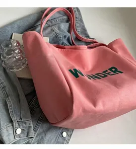 Ροζ πάνινη τσάντα tote με πράσινα γράμματα Wonder πάνω σε τζιν μπουφάν σε σκηνικό lifestyle