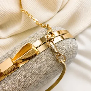 Close-up of golden metal hooks and silver glitter fabric on this elegant evening clutch