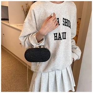 Detail of sparkly black oval evening bag with gold ring handle and bow clasp