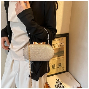 Close-up of champagne gold glitter clutch bag with bow metal clasp and ring handle
