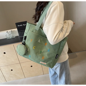 Vue détaillée du grand sac cabas en toile verte avec broderie colorée et mini pochette