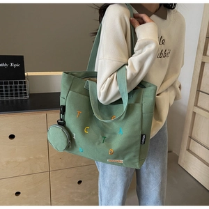 Détail du cabas en toile verte avec broderie colorée et pochette ronde zippée assortie