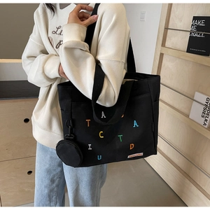 Détail d'un sac cabas en toile noire avec broderie et petit porte-monnaie