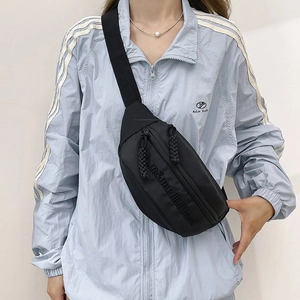 Détail du sac banane en nylon noir avec fermetures éclair et tirettes en corde tissée