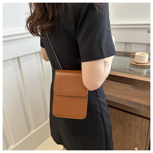 Gros plan d'un sac de téléphone vertical en cuir marron avec bandoulière chaîne métal