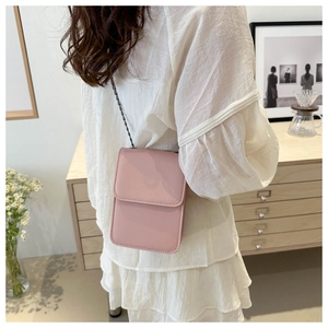Close-up of pink minimalist crossbody phone bag with black chain strap on a white dress