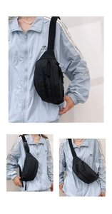 Vue détaillée du sac de poitrine en nylon noir avec sangle et texte décoratif