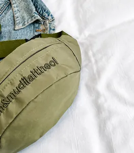 Detail of army green nylon waist bag with high-quality embroidery and metal zipper