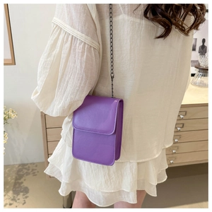 Detailed view of deep purple mini crossbody bag with sleek metal chain on model