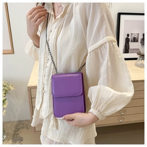 Detail of purple leather mini crossbody bag with delicate metal chain strap on model