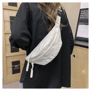 Vue détaillée du sac banane blanc en nylon avec broderie sur une chemise noire oversize
