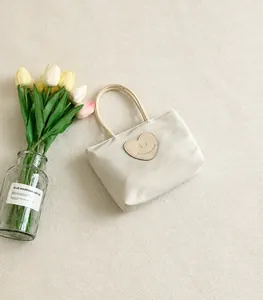 Dettaglio della borsa in nylon crema con patch cuore smiley su panno a scacchi