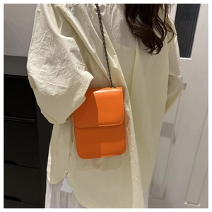 Detailed side view of orange PU leather crossbody phone bag with black metal chain strap