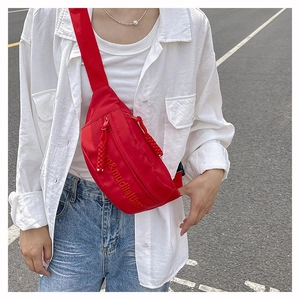 Photo de rue d'un sac banane en nylon rouge avec fermeture éclair et sangle réglable