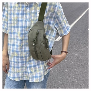 Gros plan sur le sac de poitrine en nylon olive avec fermeture éclair et logo imprimé