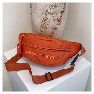 Détail d'un sac bandoulière orange en nylon avec broderie 3D et sangle réglable