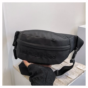 Gros plan sur un sac banane noir en nylon avec broderie discrète et sangle résistante