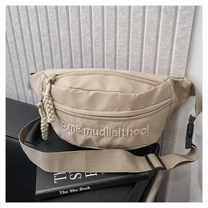 Détail d'un sac banane en nylon beige imperméable avec broderie et tirette de zip tissée